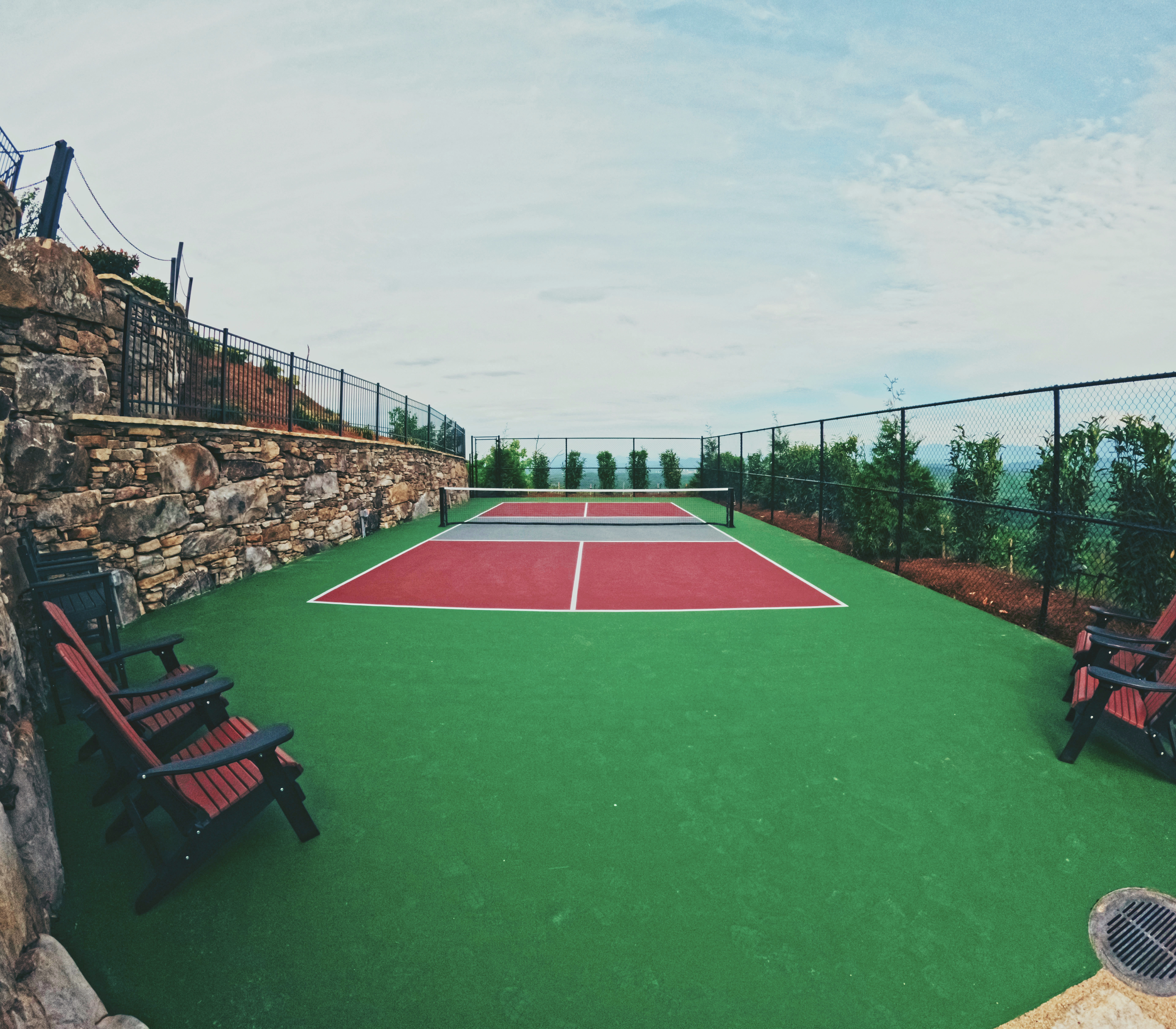 Custom pickleball court framed by stone retaining walls and mountain views.