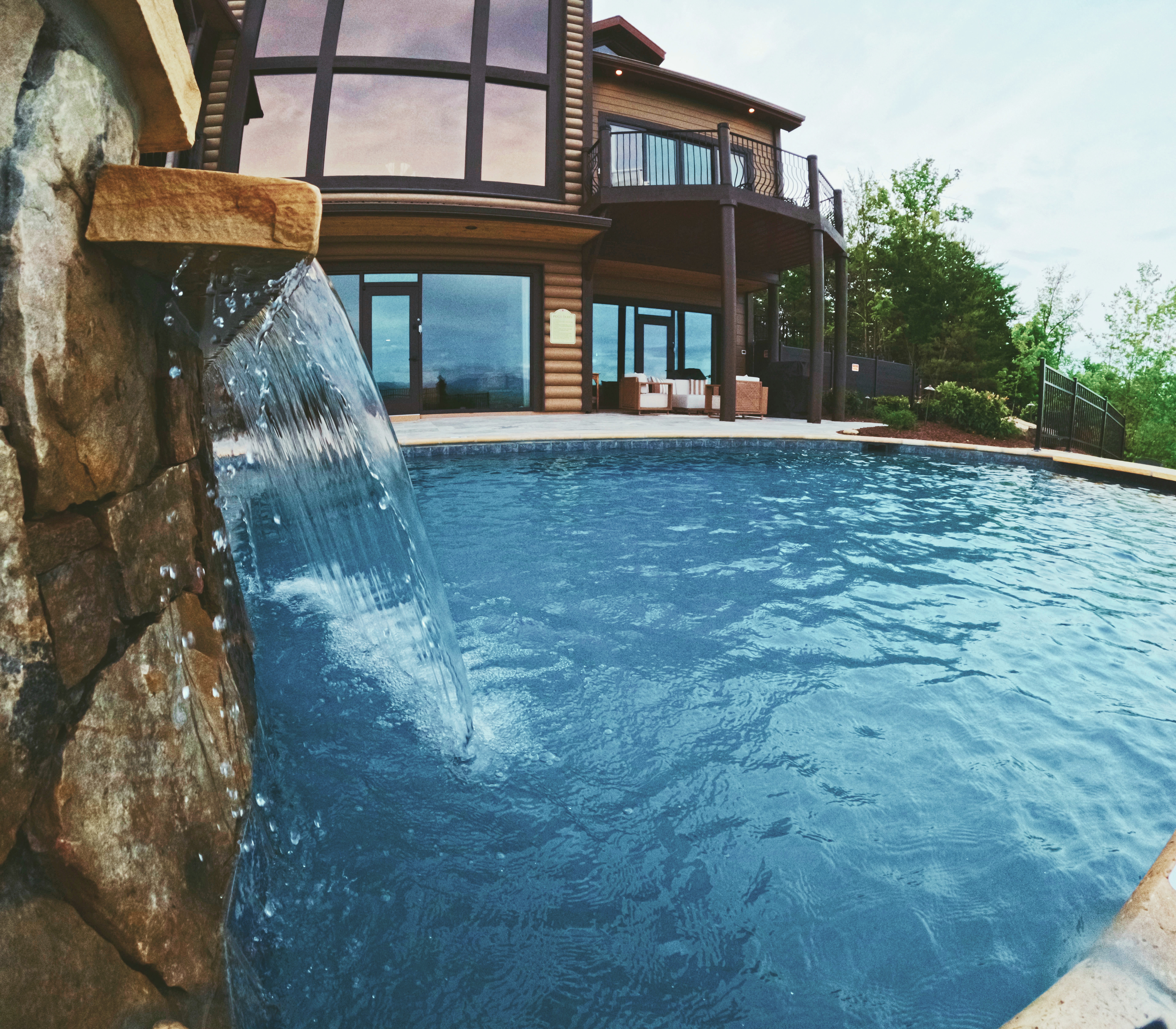 Integrated stone spa spillover flowing into a custom pool beside the mountain lodge.
