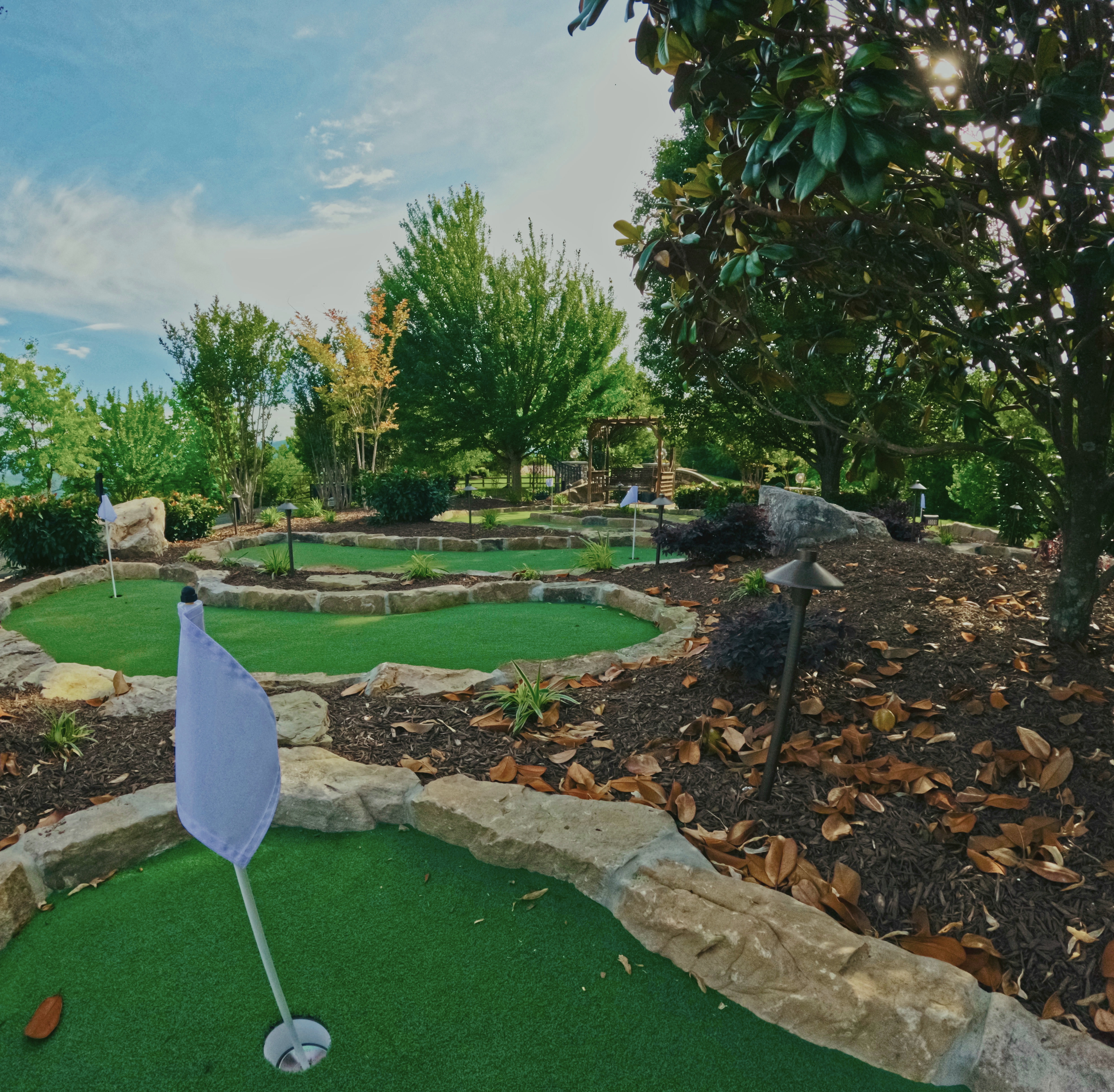 Garden putting green with natural stone edging and layered plantings.