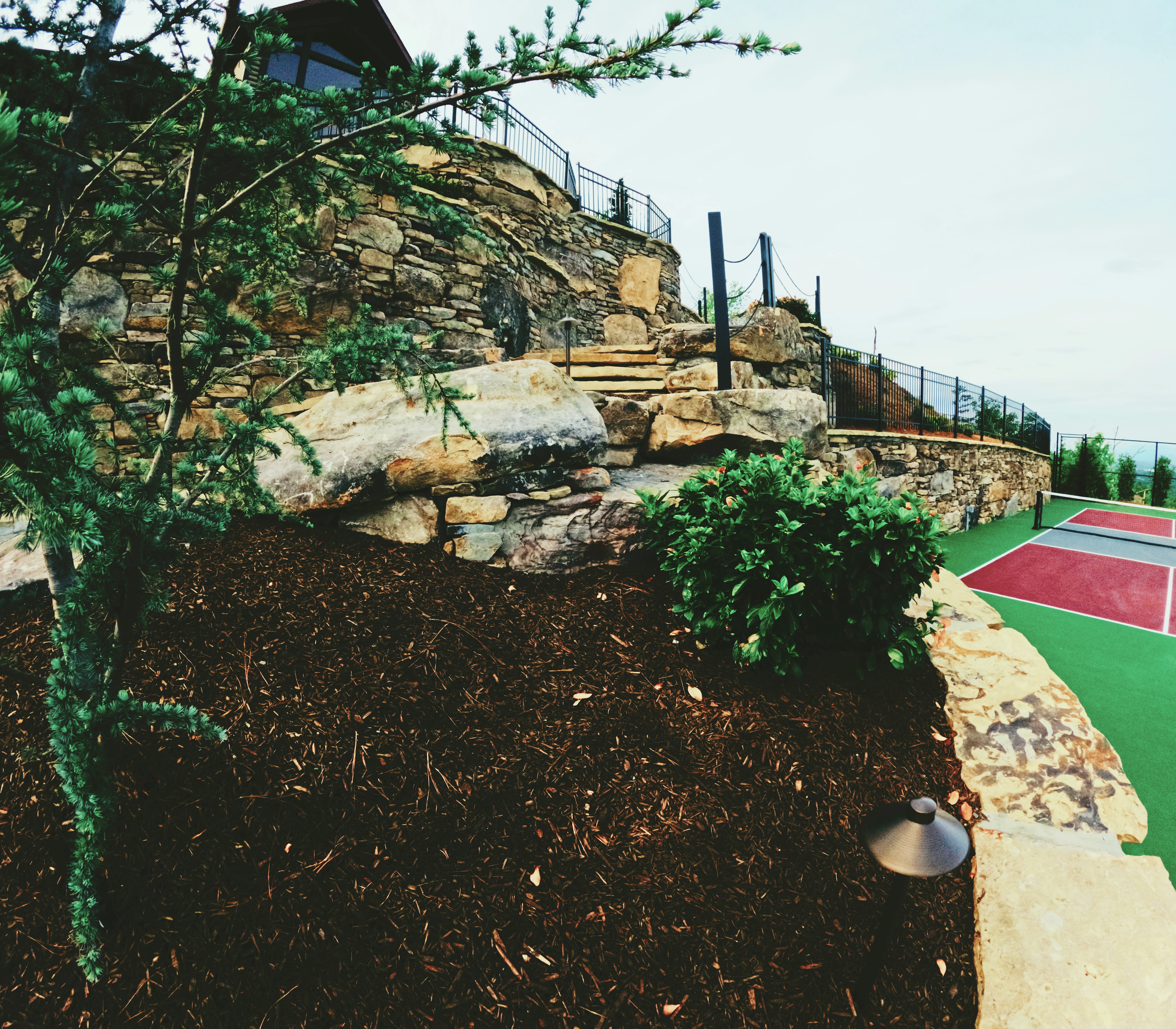 Custom stone terrace, stairs, and recreation court integration.