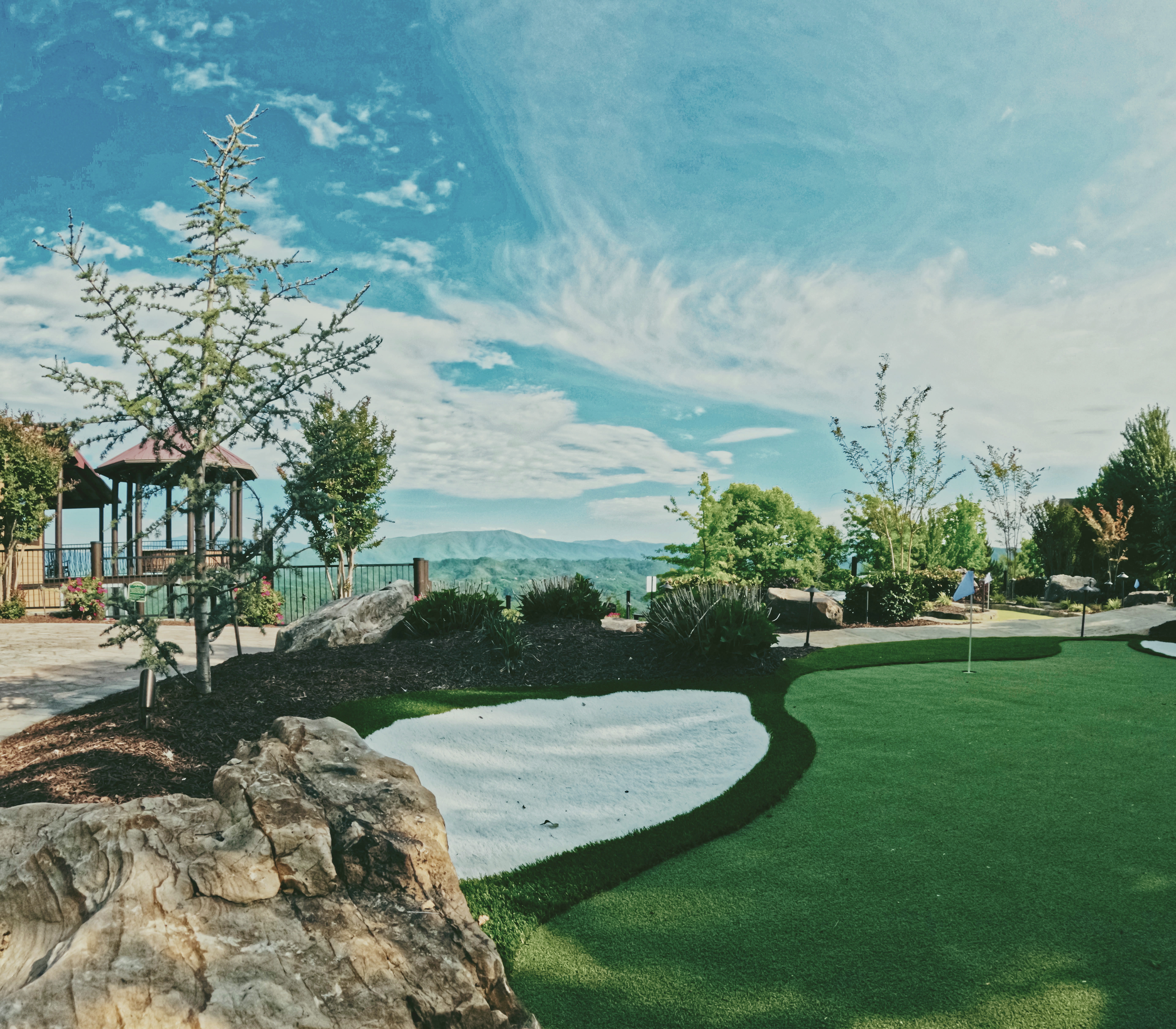 Putting green with sand trap detail and panoramic mountain views.